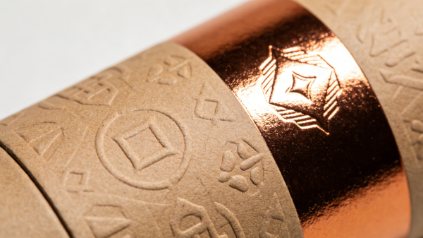 Close-up of custom rigid box with gold foil stamping, embossing, textured paper, and spot UV finish