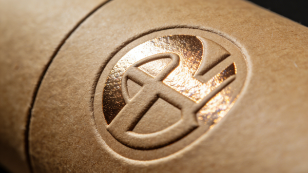 Close-up of custom rigid box with gold foil stamping, embossing, textured paper, and spot UV finish