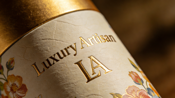 Close-up of custom paper tube packaging with gold foil stamping, embossed logo, textured specialty paper, and high-quality printing finish